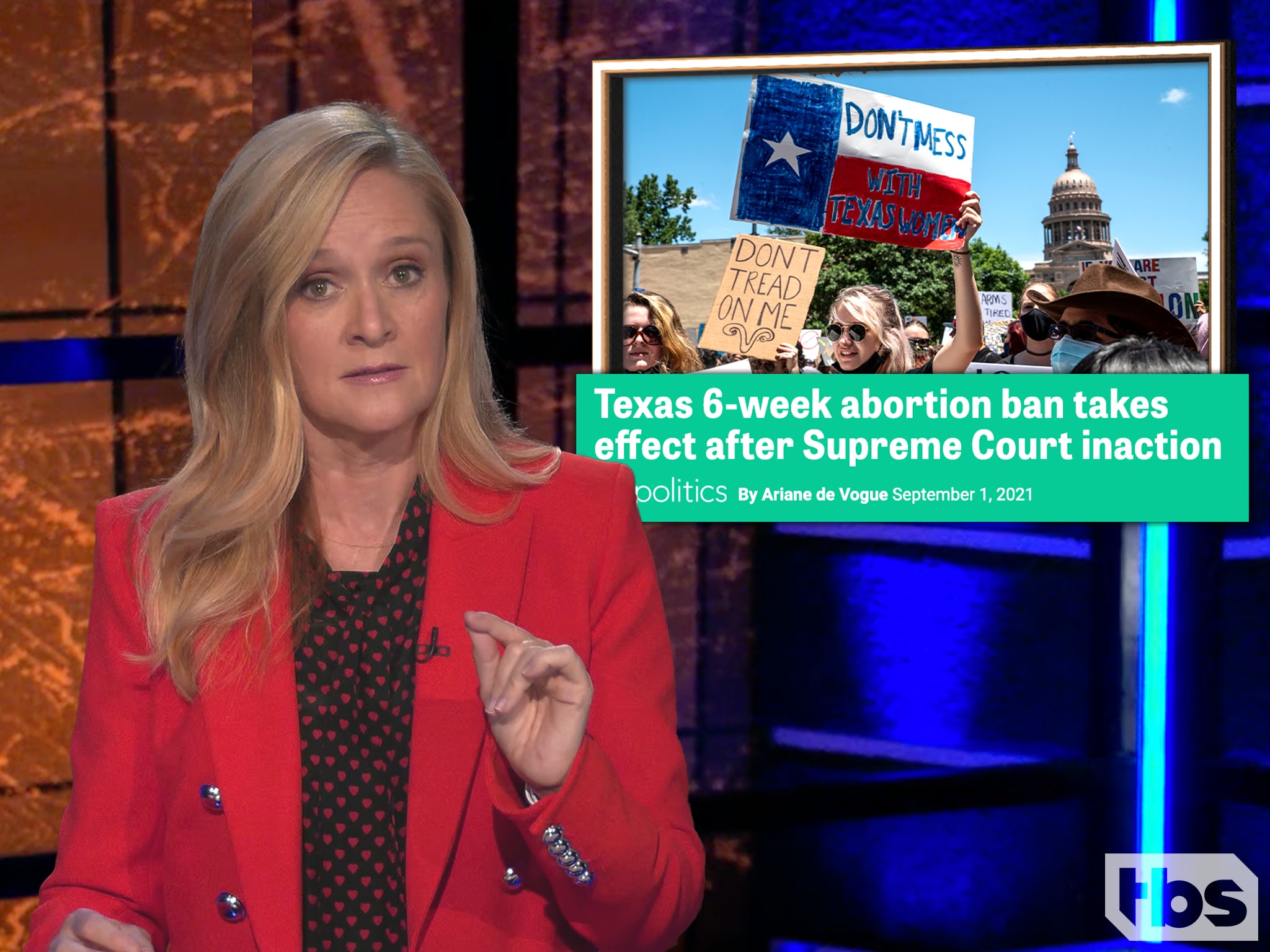 Full Frontal Samantha Bee in a red blazer with a picture to her right of a protest in Texas